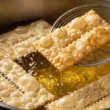 Chiacchiere di Carnevale in frittura nell'olio bollente, dorate e piene di bolle superficiali.